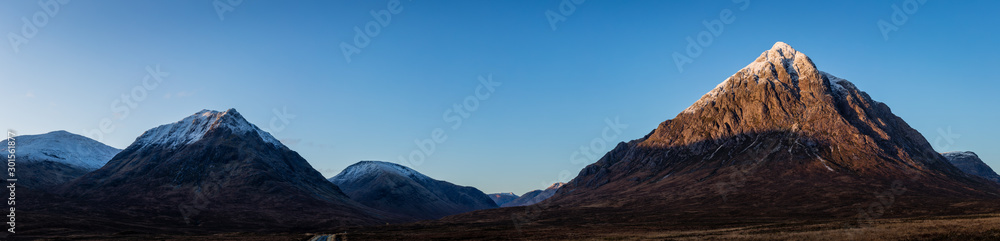 buachaille etive mor and the surrounding mountains of glencoe and rannoch moor in the argyll region of the highlands of scotland during a crisp clear blue winter sunrise