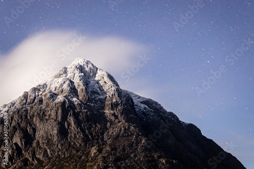 the night sky above buachaille etive mor and surrounding mountains of glencoe in the argyll region of the highlands of scotland during a clear dark sky night in autumn