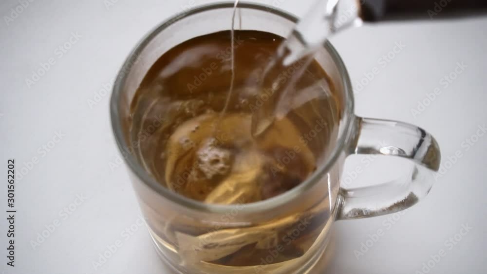 Brewing black tea bag in glass cup on white background Brewing black tea bag in glass cup on white background