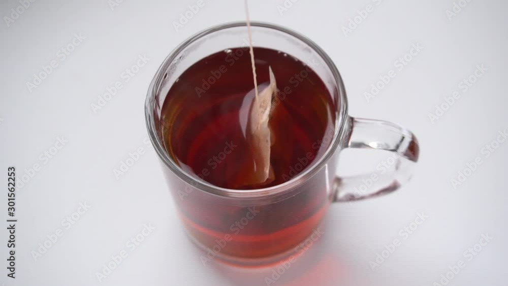 Brewing black tea bag in cup on white background Brewing black tea bag in cup on white background