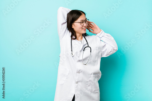 Young chinese doctor woman stretching arms, relaxed position.