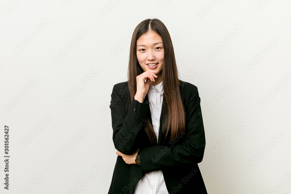 Young pretty chinese business woman smiling happy and confident, touching chin with hand. Young pretty chinese business woman smiling happy and confident, touching chin with hand.