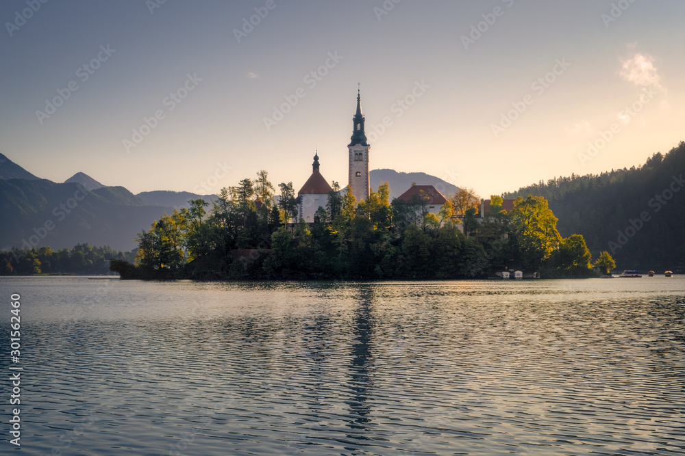 Scenic view of Lake Bled island with church and colorful autumn foliage, Slovenia