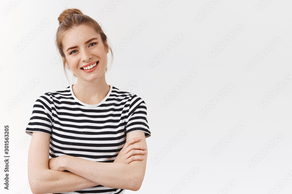 Waist-up shot lucky, confident good-looking woman with messy bun in striped t-shirt, cross hands chest, tilt head and smiling looking like professional, being self-assured and encouraged Waist-up shot lucky, confident good-looking woman with messy bun in striped t-shirt, cross hands chest, tilt head and smiling looking like professional, being self-assured and encouraged