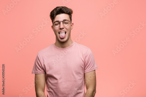 Young cool caucasian man funny and friendly sticking out him tongue.