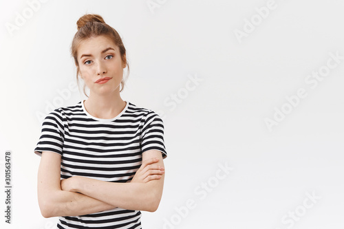 Skeptical sassy young woman in striped t-shirt with messy bun, cross hands chest and smirk, pouting look with dismay, bothered by lame pick-up line, standing white background careless