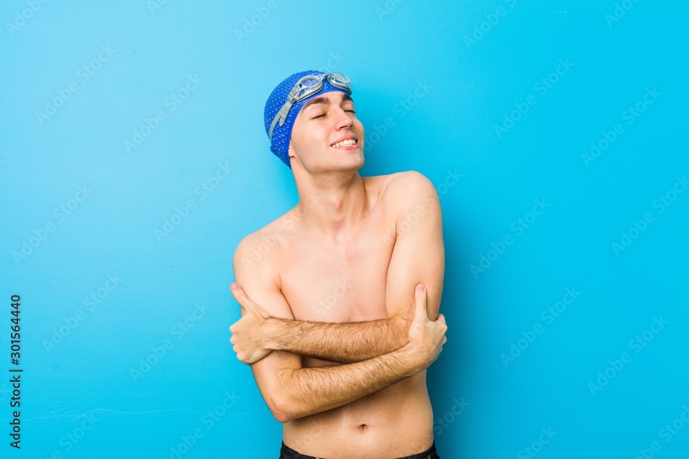 Young swimmer man hugs, smiling carefree and happy.