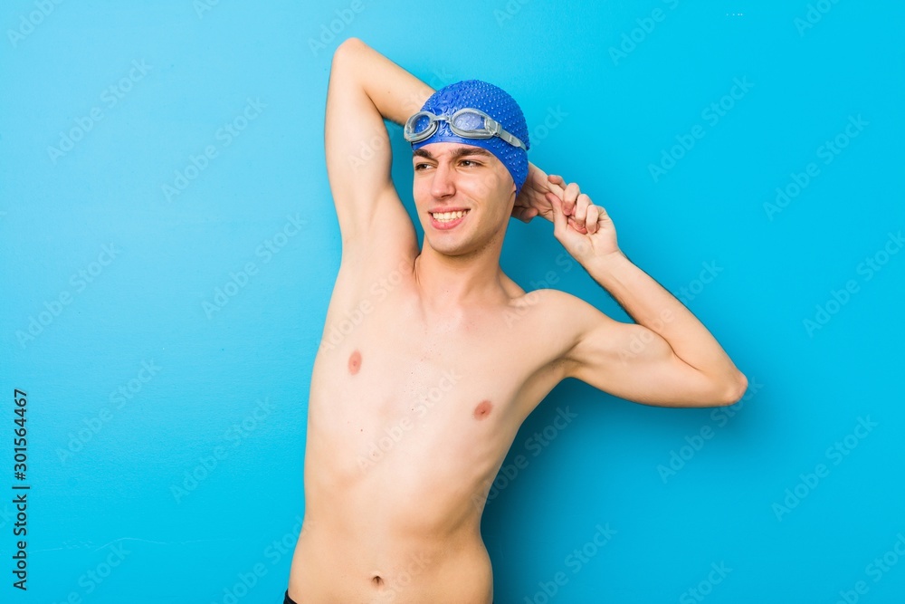Young swimmer man stretching arms, relaxed position.