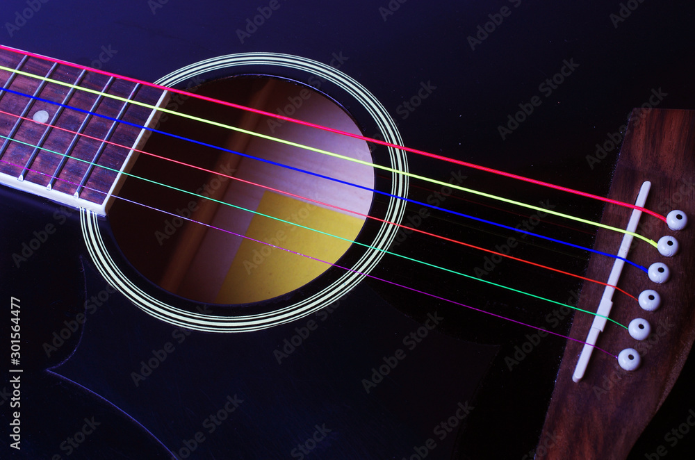 Obraz premium Black acoustic guitar with multi-colored strings. Close-up.