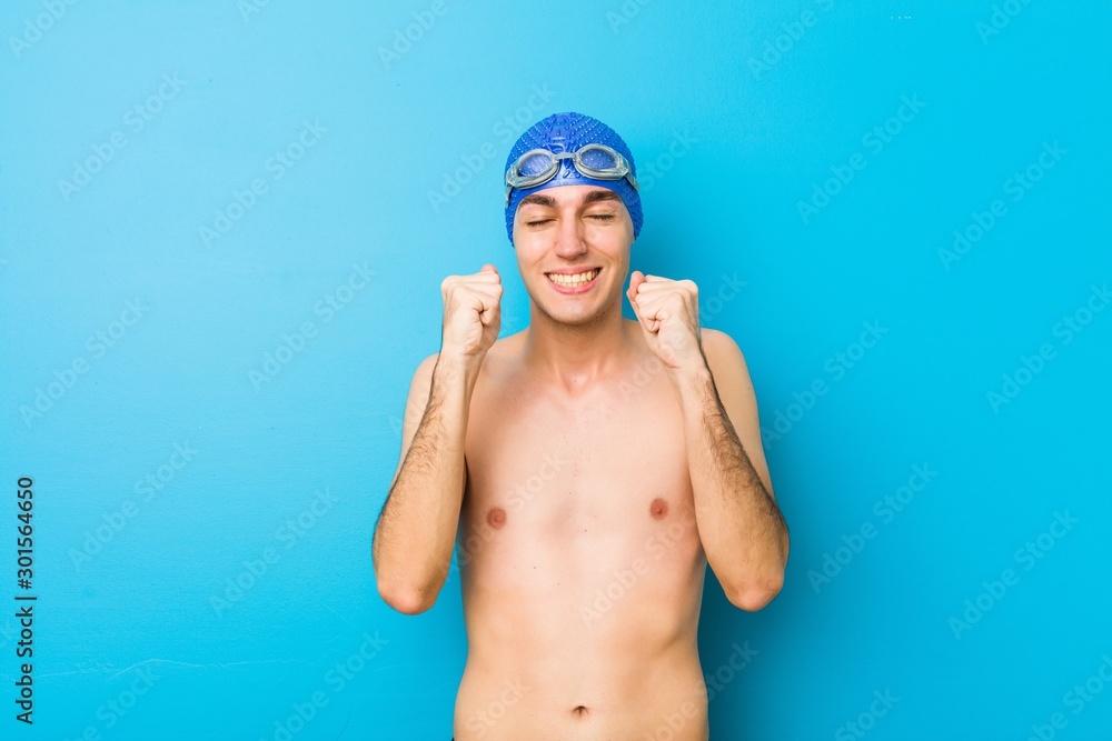 Young swimmer man raising fist, feeling happy and successful. Victory concept.
