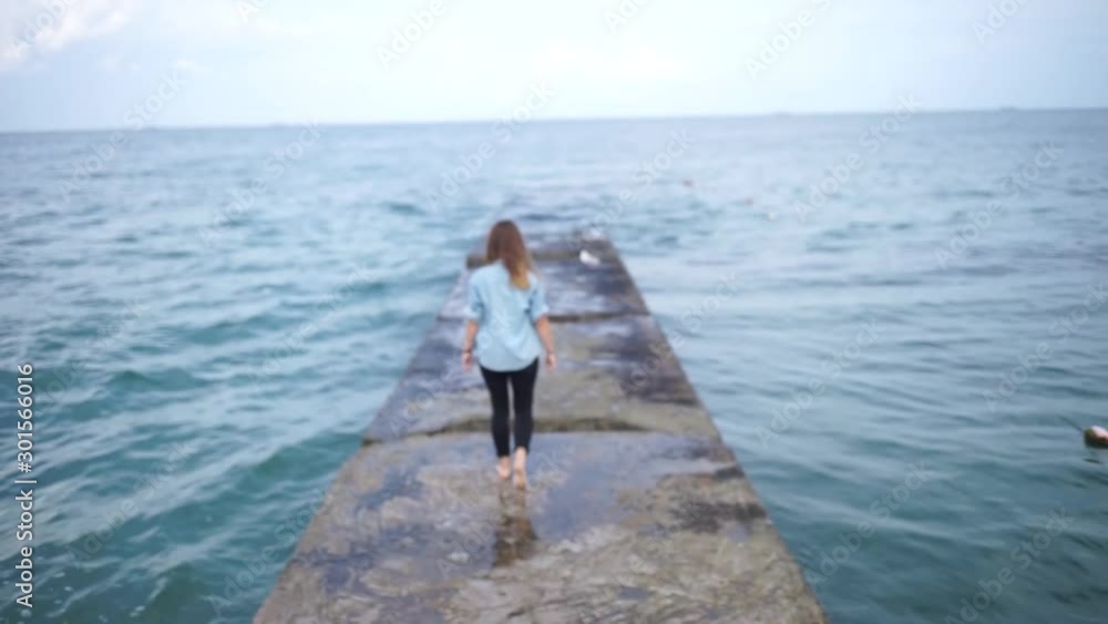Beautiful girl walking on the pier.Woman walks on stones pier in a summer day. Beautiful girl walking on the pier.Woman walks on stones pier in a summer day.