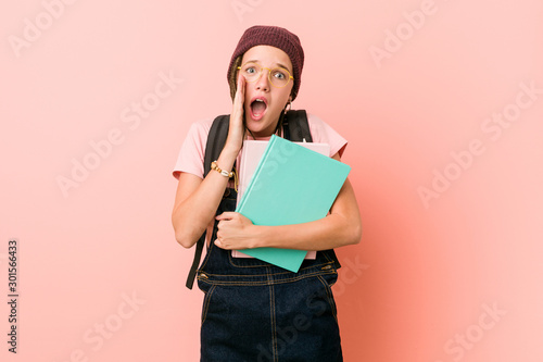 Young caucasian woman holding some notebooks shouting excited to front.