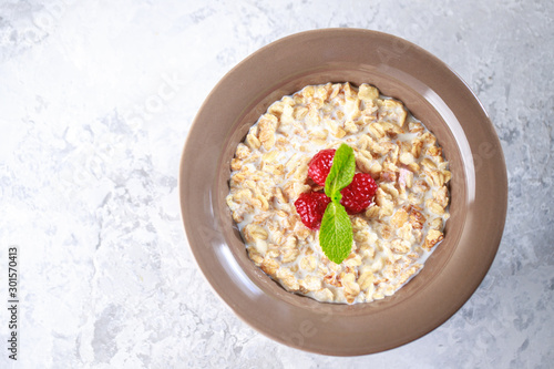 Healthy breakfast. Baked granola with milk and raspberries with mint in a plate. Tasty muesli, close-up