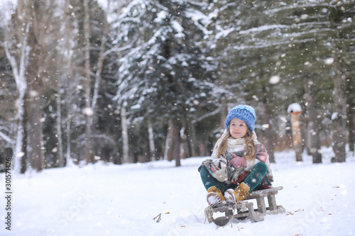 A winter fairy tale in the forest. A girl on a sled with gifts on the eve of the new year in the park. Two sisters walk in a New Year's park and ride a sled with gifts.