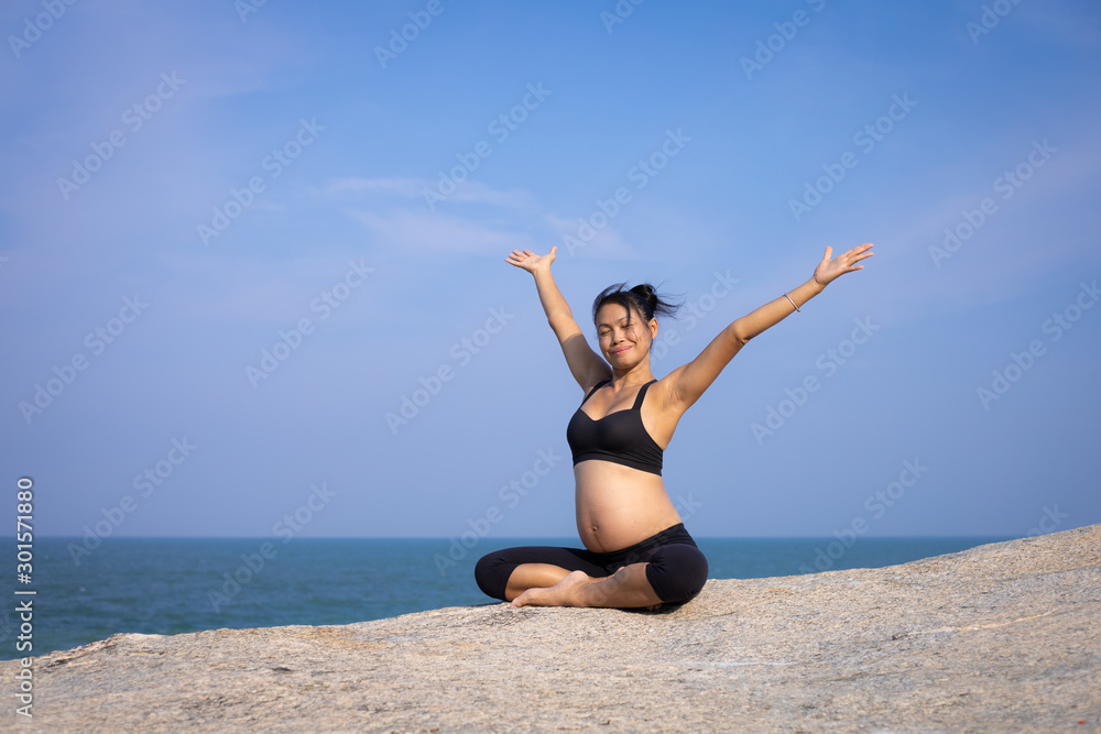 Asian pregnant woman yoga on the beach sunset summer time Asian pregnant woman yoga on the beach sunset summer time