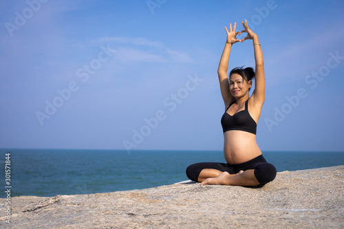  Asian pregnant woman yoga on the beach sunset summer time