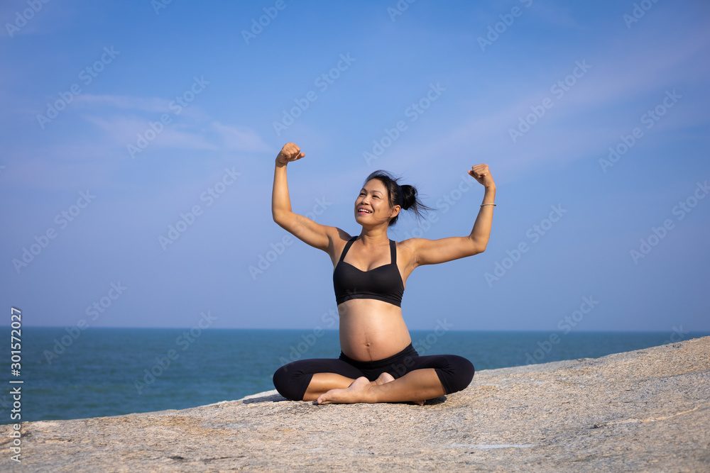  Asian pregnant woman yoga on the beach sunset summer time