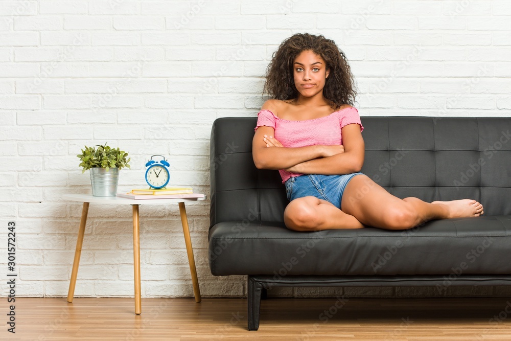 Young african american woman sitting on the sofa unhappy looking in camera with sarcastic expression. Young african american woman sitting on the sofa unhappy looking in camera with sarcastic expression.