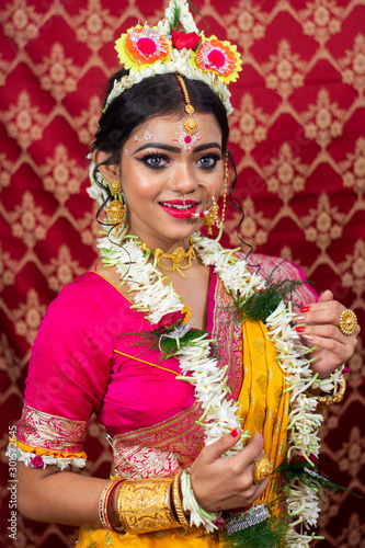 Traditional Bengali woman in wedding sari and makeup with flowers and garland, Indian woman looking at camera