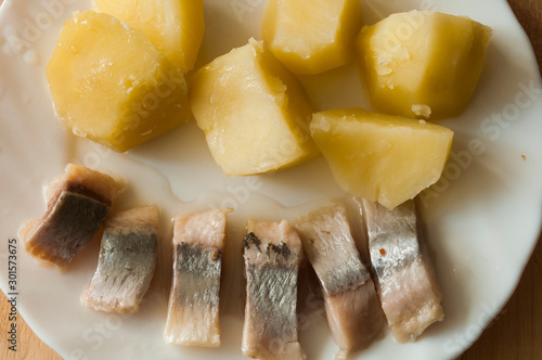 Salted herring and boiled potatoes on white plate