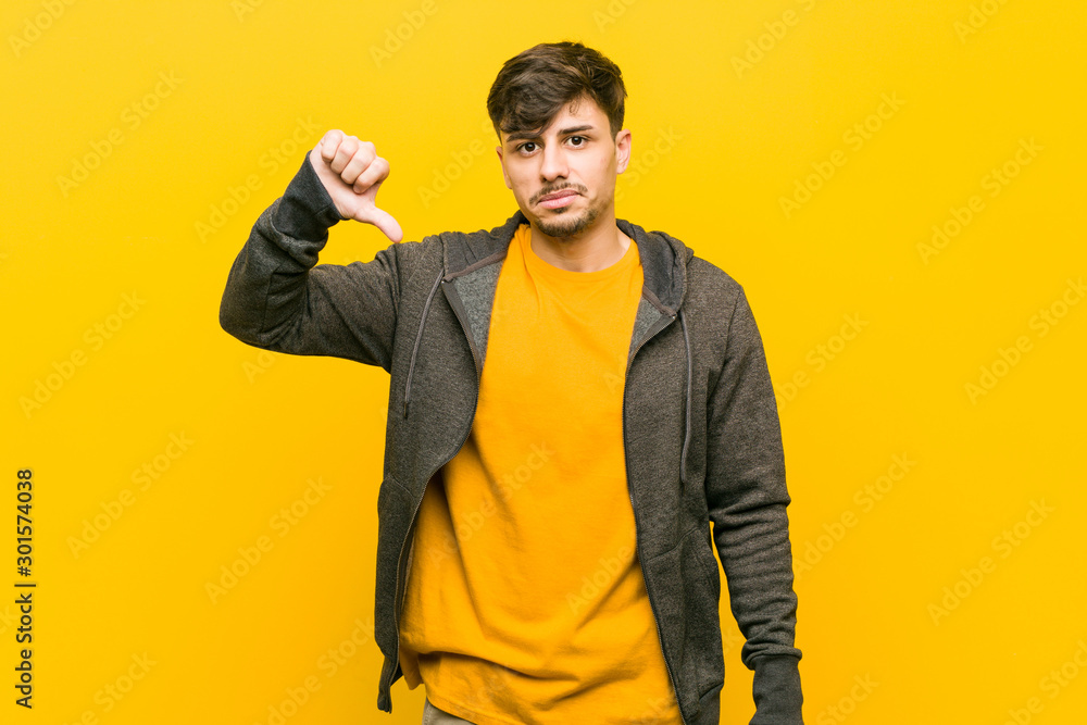 Young hispanic casual man showing a dislike gesture, thumbs down. Disagreement concept. Young hispanic casual man showing a dislike gesture, thumbs down. Disagreement concept.