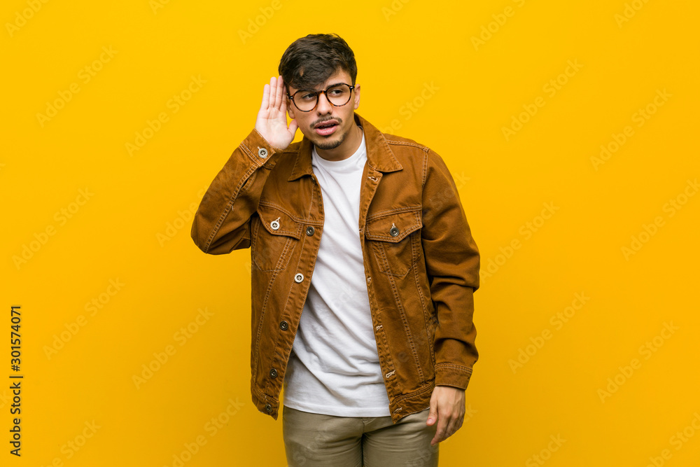 Fototapeta premium Young hispanic casual man trying to listening a gossip.