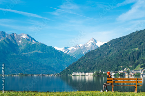 Girl rest after training on the bench near the lake Zell am See high in the Alpine mountains in Austria. dressed in a black tracksuit for, copy space