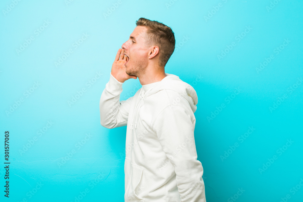 Young caucasian sport man shouting and holding palm near opened mouth. Young caucasian sport man shouting and holding palm near opened mouth.