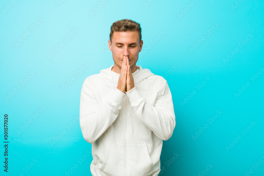 Young caucasian sport man holding hands in pray near mouth, feels confident. Young caucasian sport man holding hands in pray near mouth, feels confident.