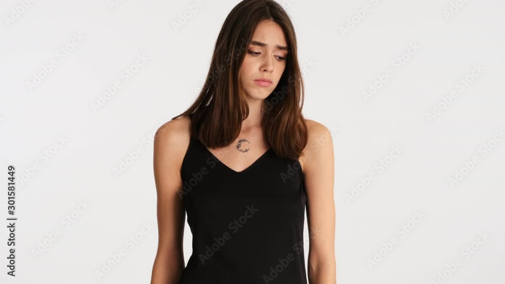 Young offended brown haired woman sadly posing over white background Young offended brown haired woman sadly posing over white background
