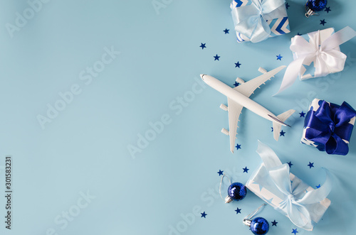 Christmas or New Year travel concept. Toy airplane with passports and gift boxes on blue background.