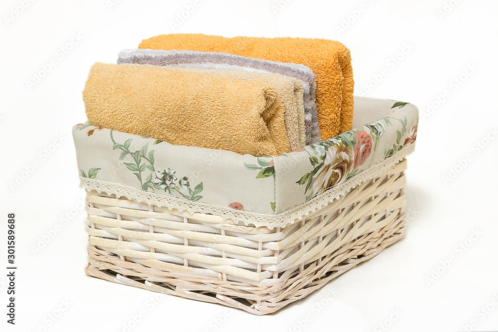 Light wicker basket, terry towels in a basket isolated on a white background.