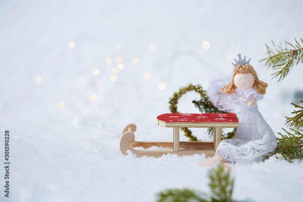 Christmas background. Doll angel, Sled toy, Heart made of fir on snow with bokeh Copyspace