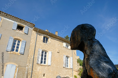 Documentary image. Joucas. Luberon. Provence. France. October 05. 2019. The gigantic man sculpture looks in the direction of the window of the house opposite. In the open window toy bears.  photo