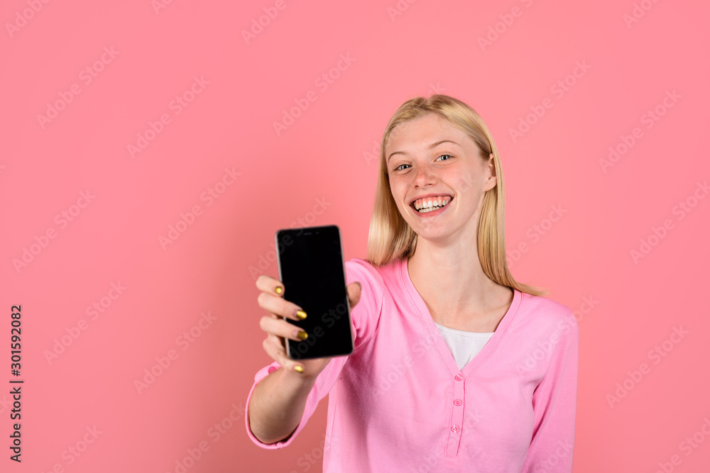 Happy girl holds smartphone with empty screen. Communication and technology concept. Smile girl with mobile phone. Black Friday, cyber Monday. Advertising new model. Beautiful woman shows smart phone. Happy girl holds smartphone with empty screen. Communication and technology concept. Smile girl with mobile phone. Black Friday, cyber Monday. Advertising new model. Beautiful woman shows smart phone.