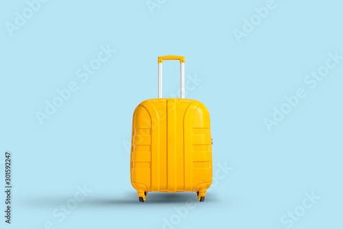 Yellow suitcase on a blue background. Travel and vacation concept in triples. Flat lay, top view photo