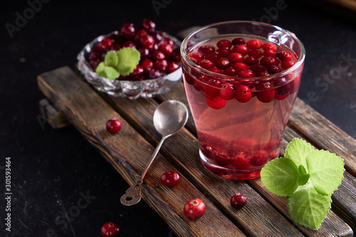 cranberry juice with honey in a cup, cranberries in sugar. On a dark wooden background Copyspace