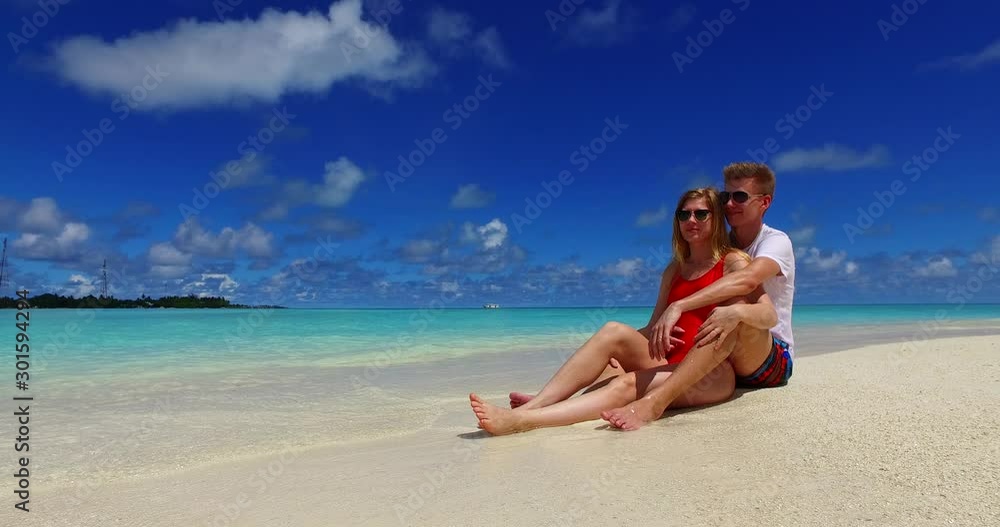 summer romance concept. Young couple sitting on the white sand beach and cuddling, Caribbean summer romance concept. Young couple sitting on the white sand beach and cuddling, Caribbean