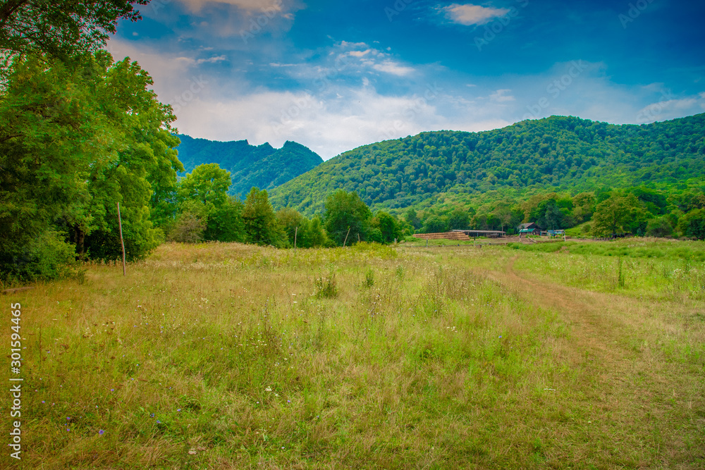 Field with green grass on the background of mountains. Republic Of Adygea, Russia. Field with green grass on the background of mountains. Republic Of Adygea, Russia.