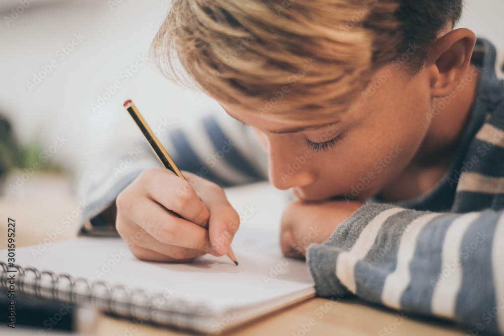 Student drawing with pencil on the notebook. Boy doing homework writing on a paper. Kid hold a pencil and draw a manga at home. Teen drawing sitting at the table. Education art talent ability concept. Student drawing with pencil on the notebook. Boy doing homework writing on a paper. Kid hold a pencil and draw a manga at home. Teen drawing sitting at the table. Education art talent ability concept.