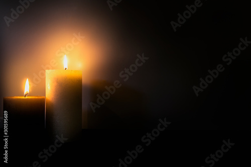 Two burning brightly candles in the dark shadow, space for text romantic colorful concept background