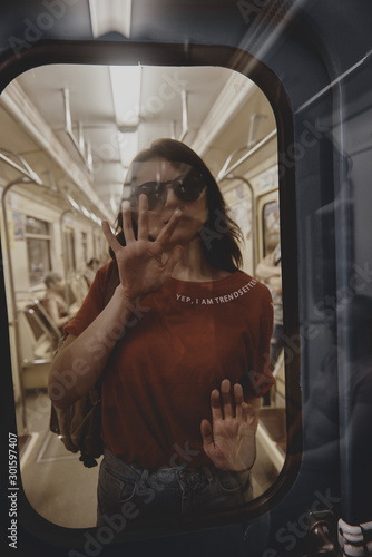 Beautiful girl in a red shirt and blue jeans in a subway train car.