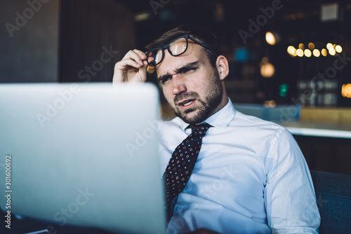 Puzzled businessman with angry expression on face confused with received email from employee with data information, unhappy male professional checking documentation via laptop computer using 4g photo