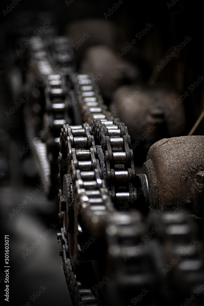 An iron chain on the gears of an old machine, photographed close up. An iron chain on the gears of an old machine, photographed close up.