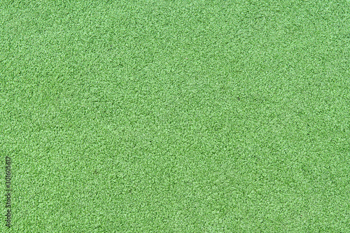 A fragment of artificial carpet with imitation of bright green grass lawn. Background. Pattern.