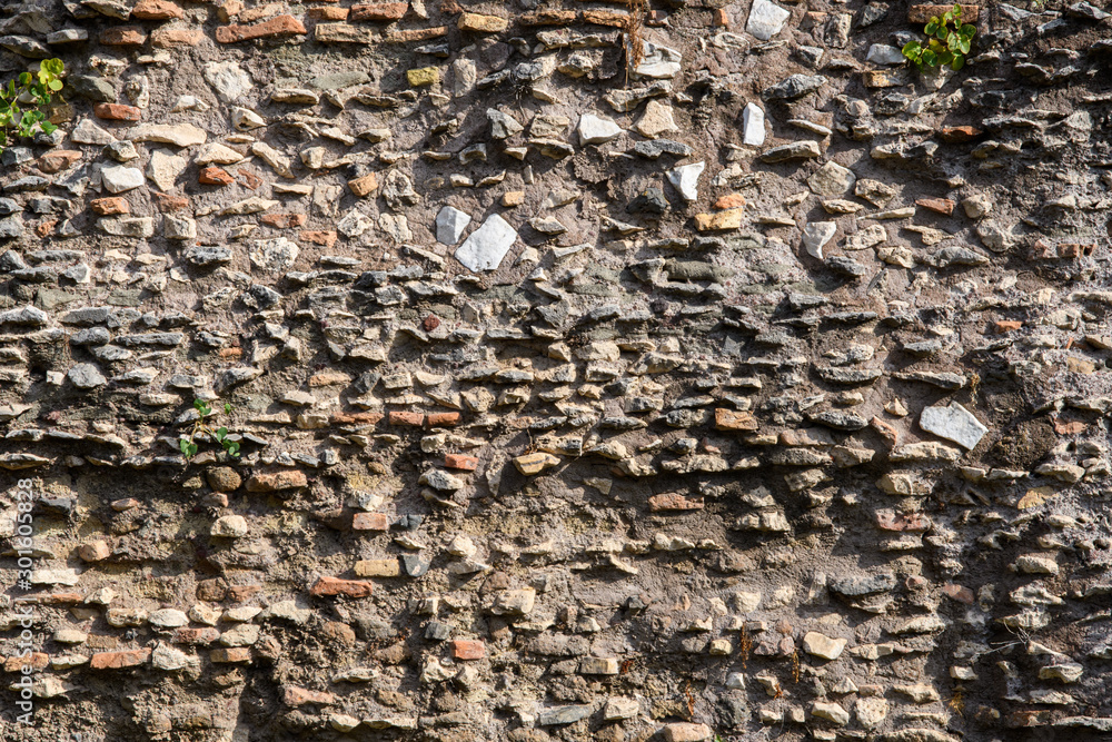A fragment of the original masonry of raw stones built by ancient Rome. Background. Pattern. Ocher, brown. A fragment of the original masonry of raw stones built by ancient Rome. Background. Pattern. Ocher, brown.