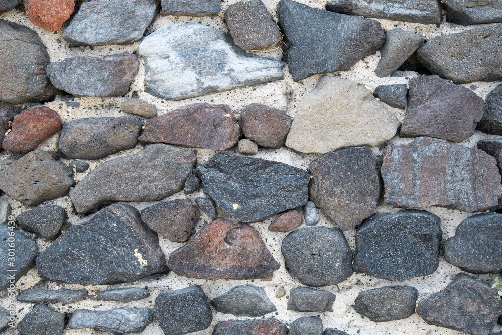 A fragment of an old stone wall made of rough stones. Background. Gray.