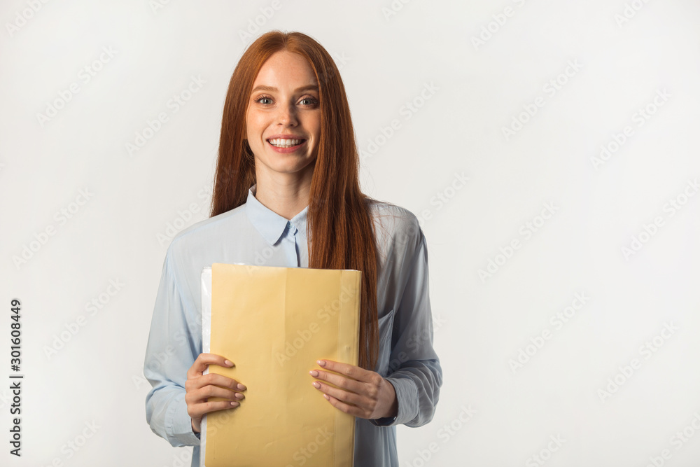beautiful young woman with red hair with a folder of documents in hand beautiful young woman with red hair with a folder of documents in hand