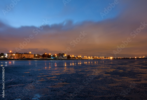 Twilight with starburst effects from street lights. Low tide along Sandymount Strand beach, Dublin, Ireland. Urban view during evening nightfall © Nicola.K.photos