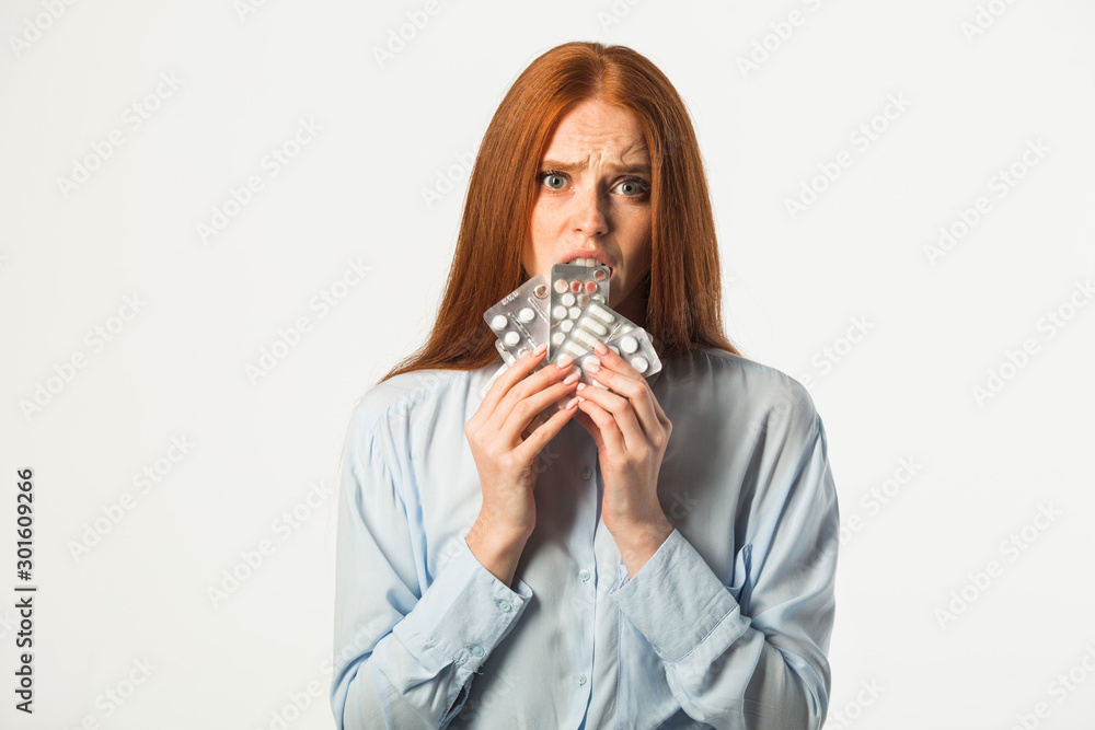 beautiful young woman with red hair with pills in hands on a white background beautiful young woman with red hair with pills in hands on a white background